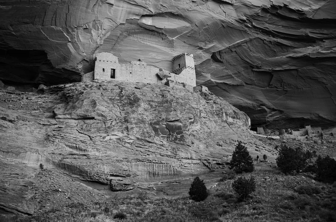 A view of Tse Yaa Kin from one of the alluvial terraces southwest of the site. In the foreground are piñon pines and junipers; in their day, the beams jutting from the tall tower likely supported balconies.