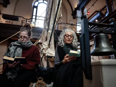 Two women follow along during the Moby Dick reading marathon at the&nbsp;New Bedford Whaling Museum.