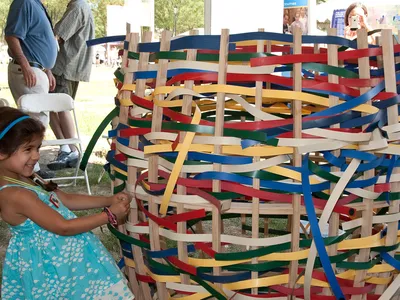 A young girl pulls strands on an oversized, multicolor basket.